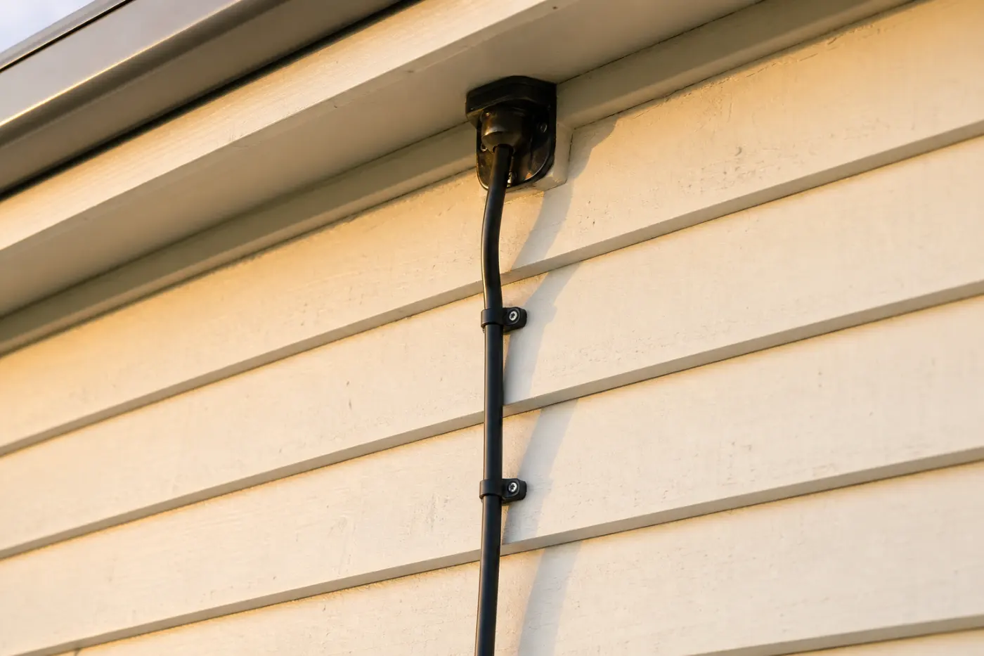 Tidy exterior cable run with weatherproof entry gland on a weatherboard farmhouse wall