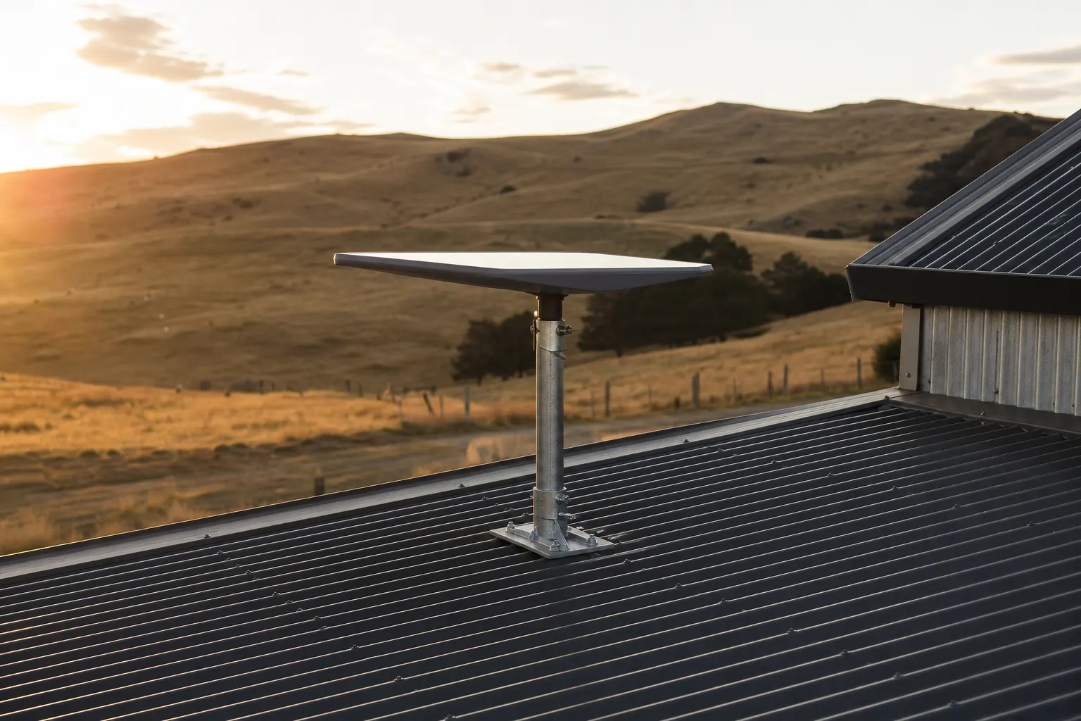 Starlink dish on a galvanised pole mount fixed to a corrugated iron farmhouse roof, golden hill country behind